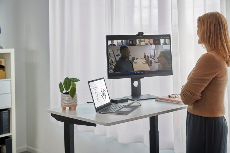 A remote employee attends an online meeting with colleagues who are in an office conference room.