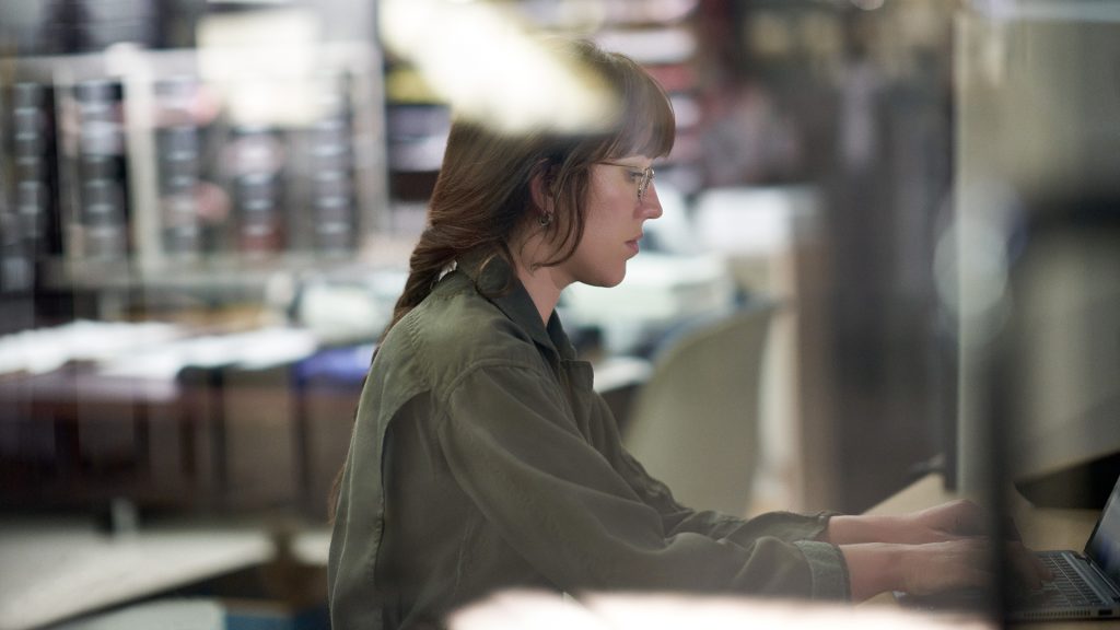 Eine Frau arbeitet an einem Schreibtisch mit ihrem Laptop