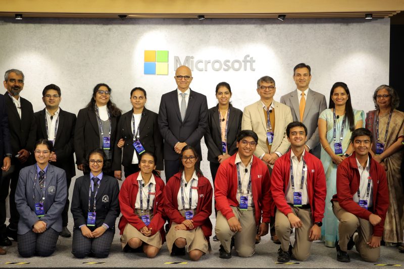 A group of people posing for a photo with the Microsoft logo on the wall behind them
