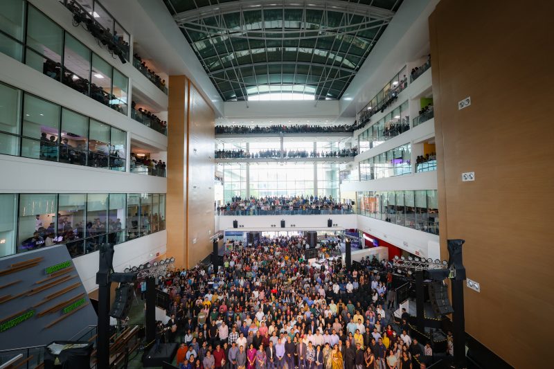 An aerial shot of Satya Nadella with hundreds of employees standing with him and on balconies across multiple floors in the atrium of Microsoft’s India Development Center building in Hyderabad