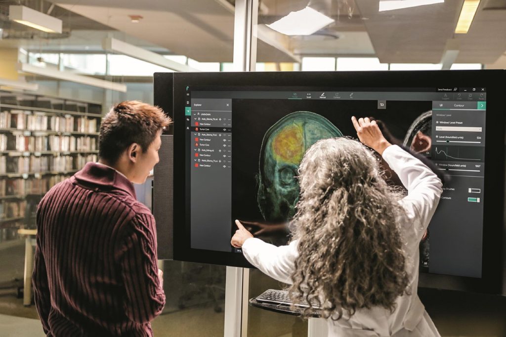 A doctor demonstrates a Surface Hub to a colleague