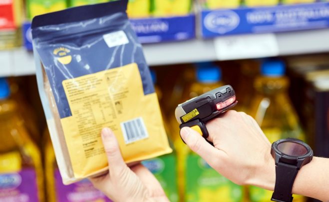A retail worker using a hand held scanner to check a barcode.