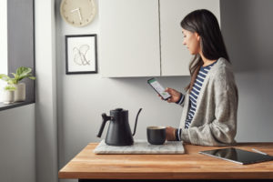 Lady standing in kitchen on smart phone