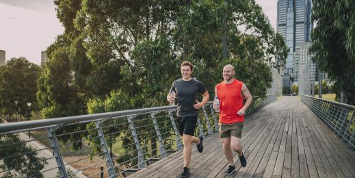 Two male friends jogging in a city park.