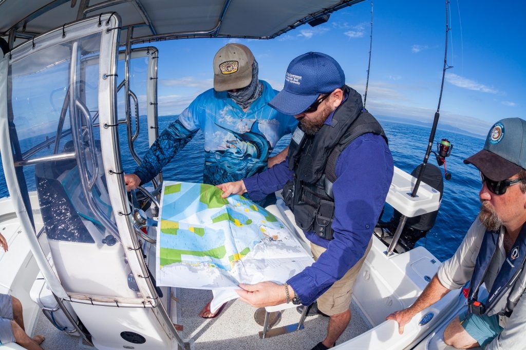 Two QLD Department rangers on a boat overseeing a map
