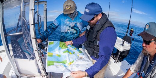 Two QLD Department rangers on a boat overseeing a map