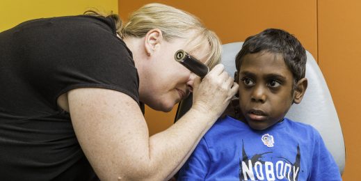 Adult female running an ear test exam for an Indigenous child