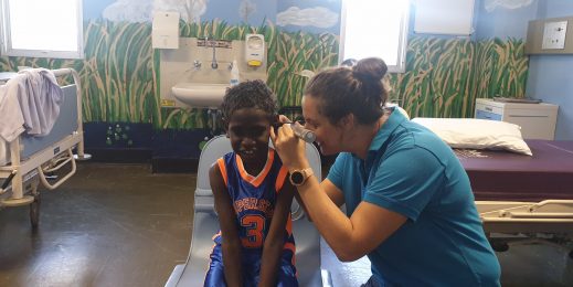 Health worker performing an ear test for an Aboriginal child