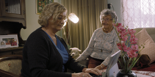 A nurse using a Surface Laptop, assisting an elderly patient