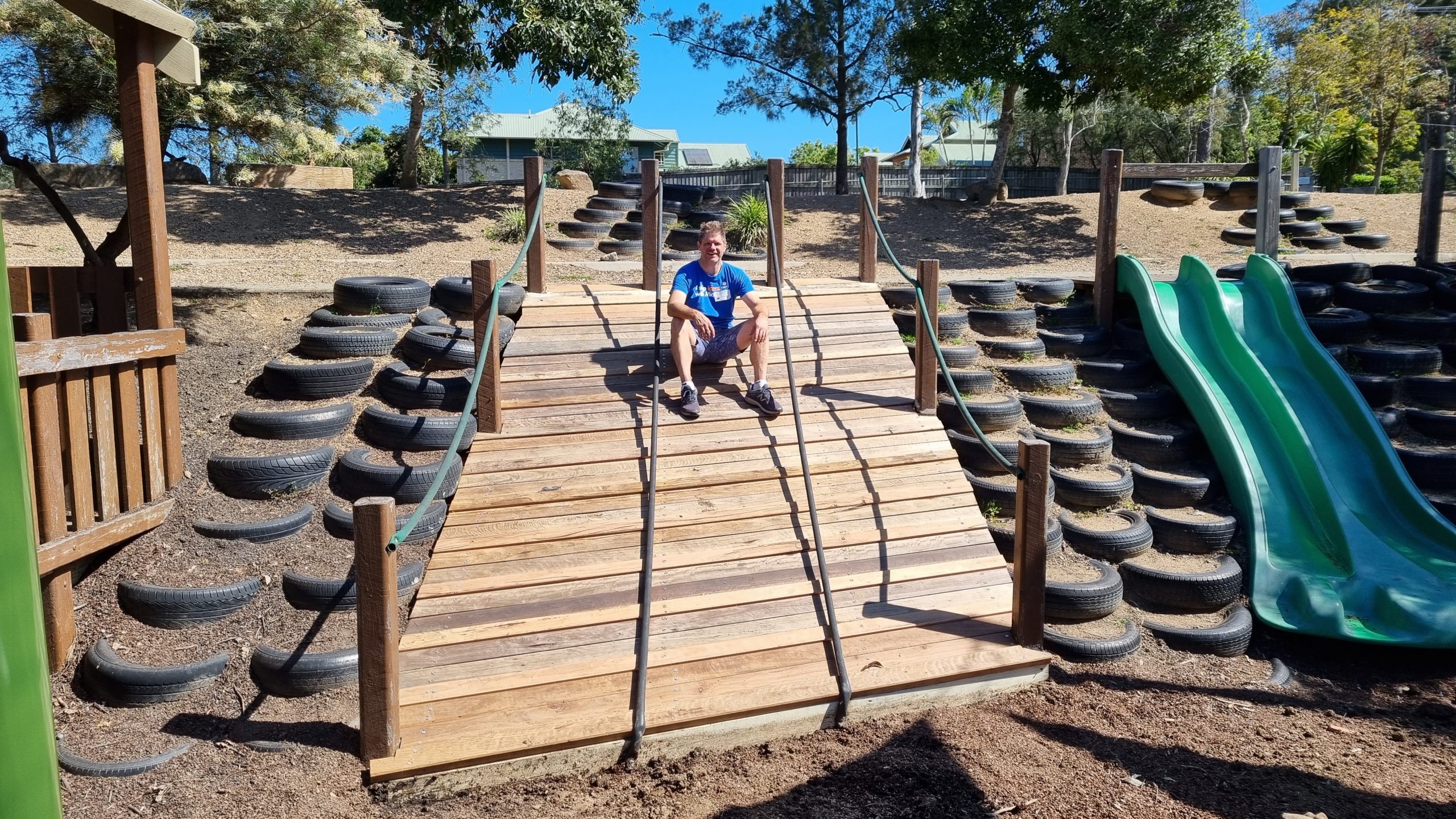 Adult male sitting on the top of a newly renovated kid's playground