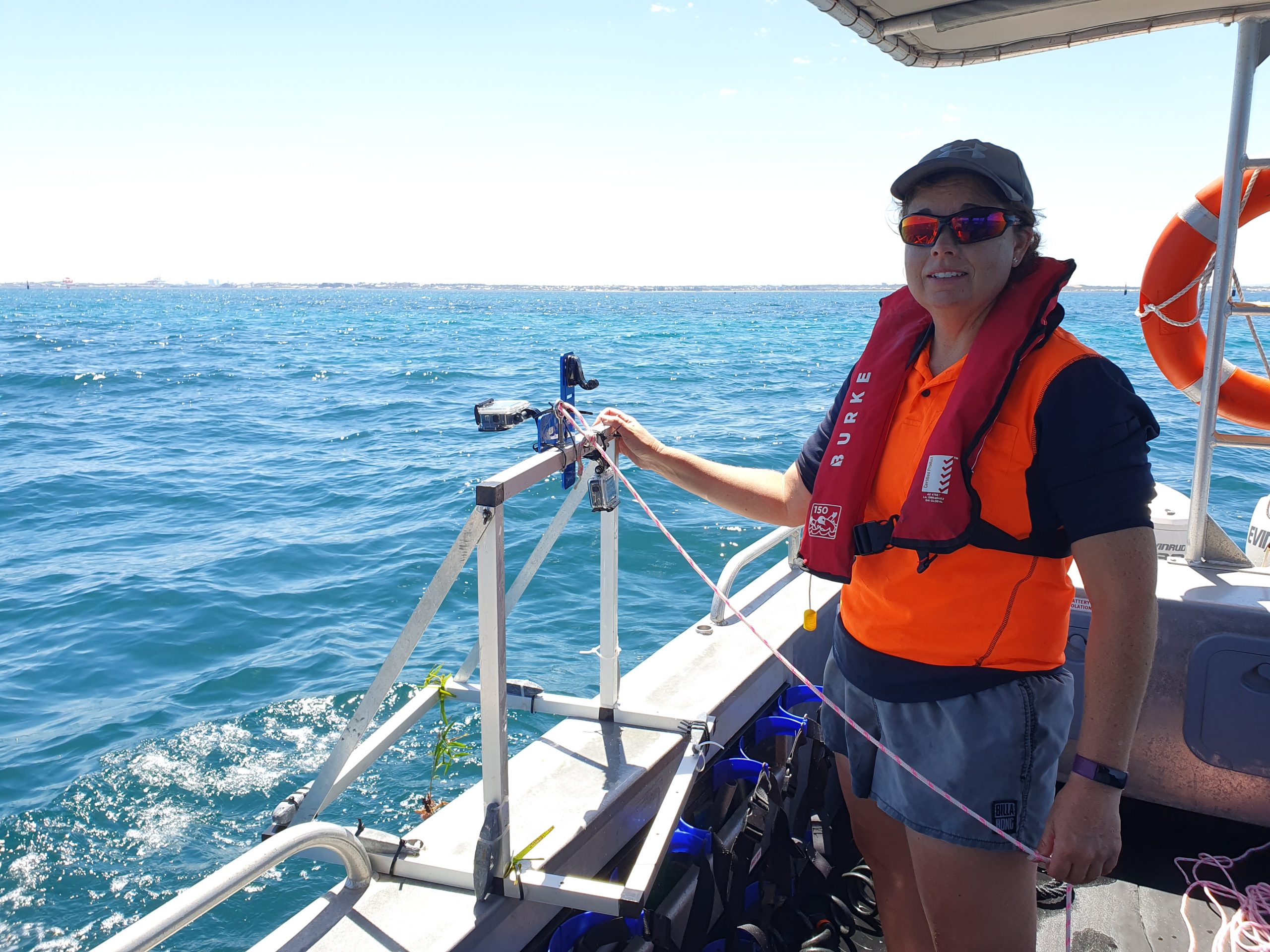Adult female, Renae Hovey, wearing a life safety vest and deploying smart cameras in the ocean