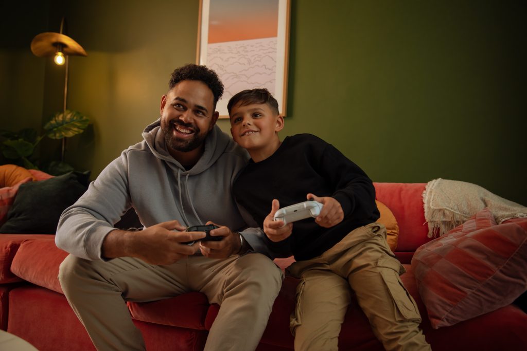 Adult male and young boy playing with Xbox controllers