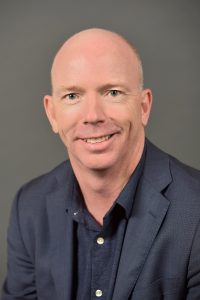 Image of a Paul Murphym CIO of GHD - He is wearing a navy blue shirt and jacket. 