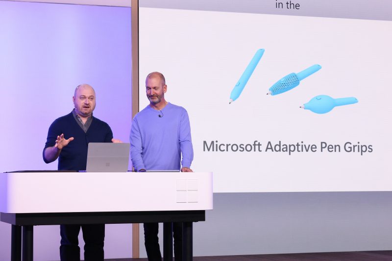 Image of Brett Ostrum, Microsoft corporate vice president for Surface devices, speaking on stage with Solomon Romney, Microsoft accessibility program manager.