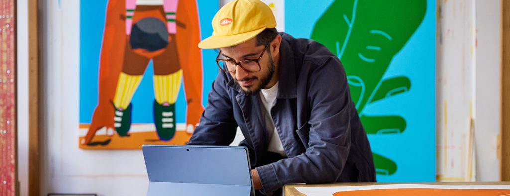Um homem está sentado em frente a um mural colorido a trabalhar num tablet.