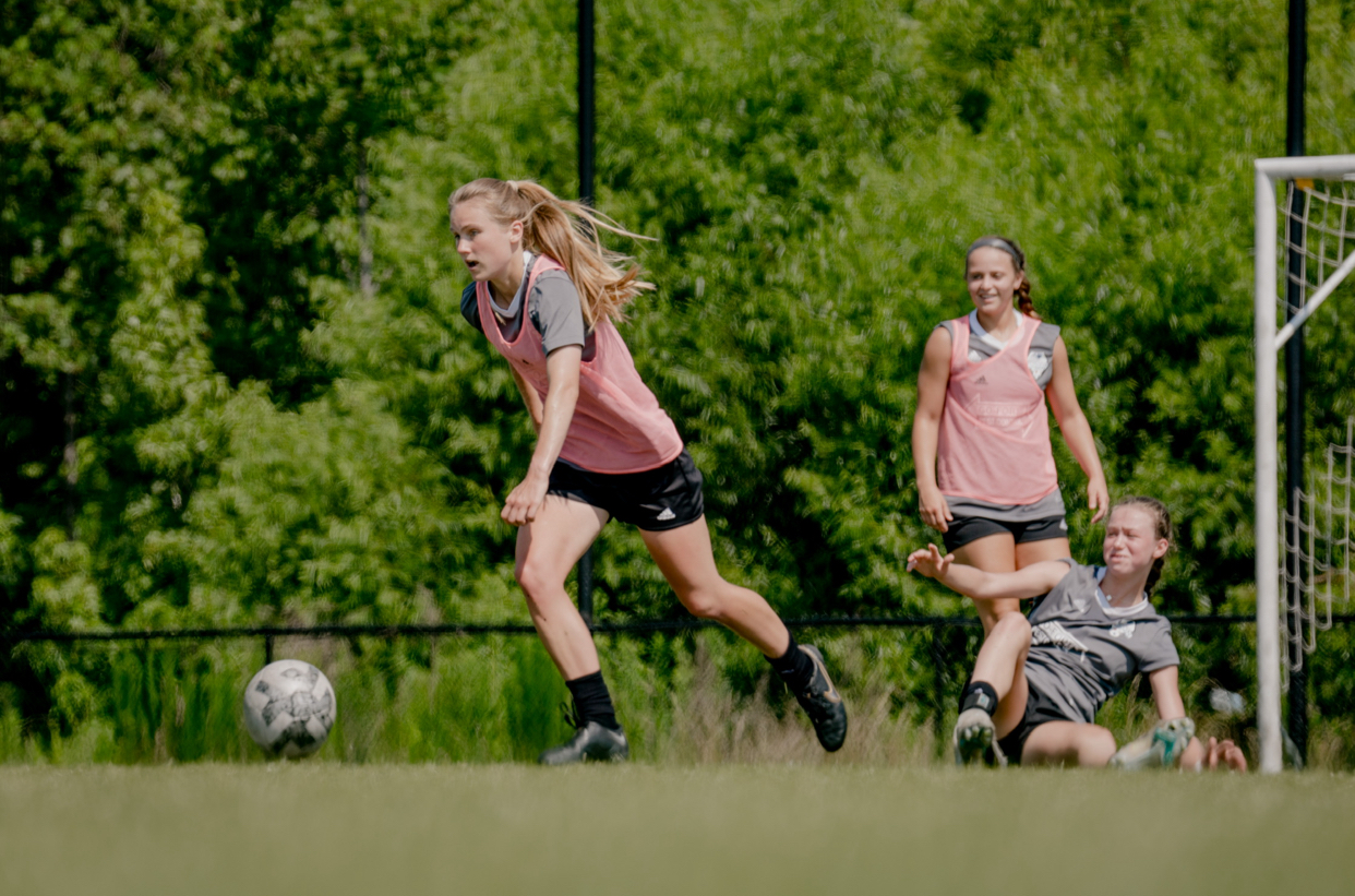 Three girls play soccer
