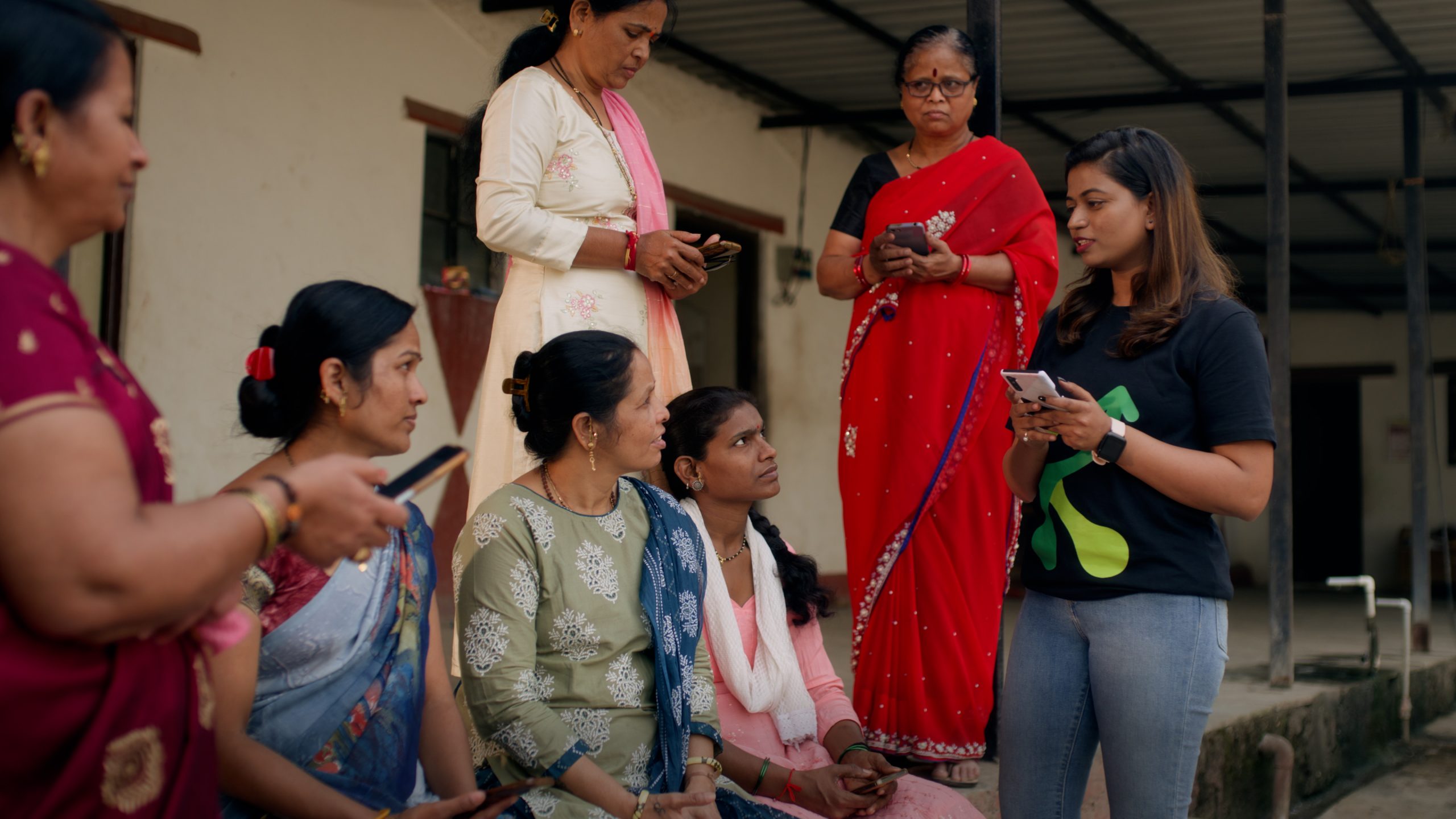 Group of women sitting on an outdoor step learning how to use an app on their smartphone