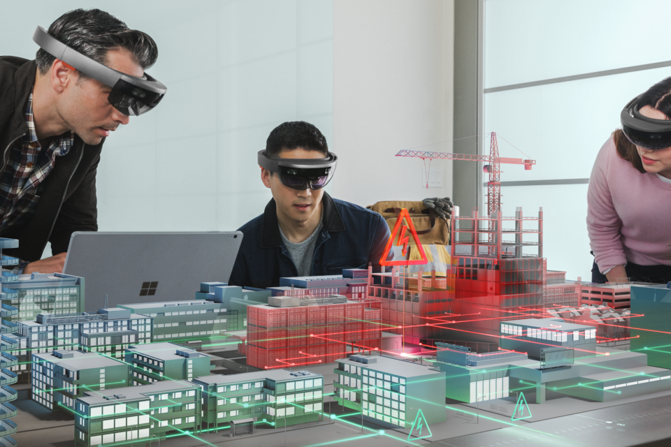 Three people wearing HoloLens looking at a virtual city on a table