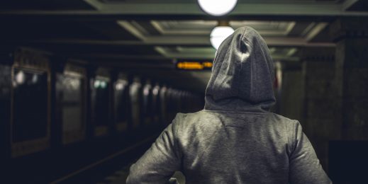 Person wearing hoodie in dark underground train station