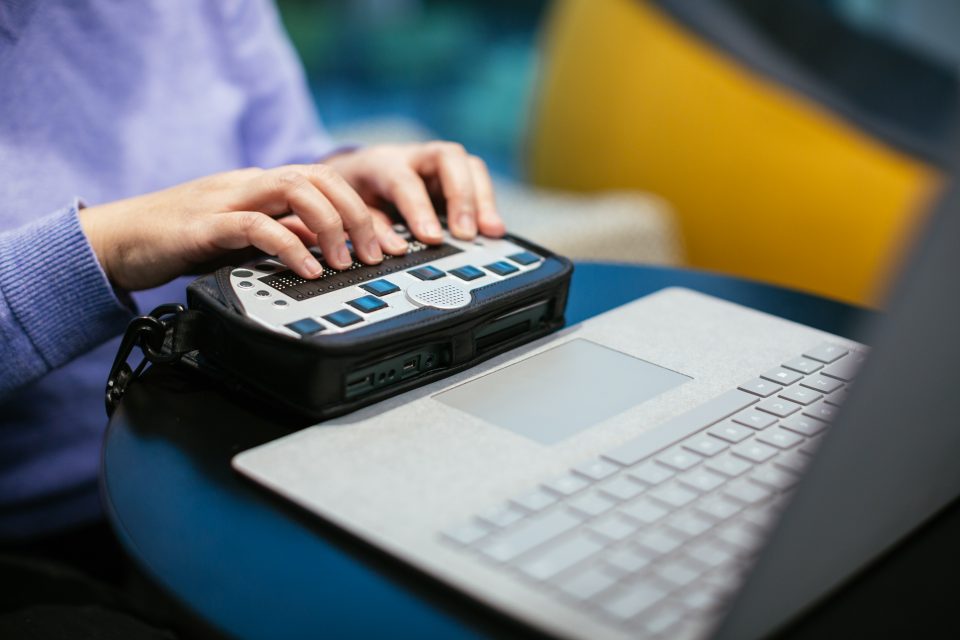 A woman types on a braille keyboard while using a Surface Book