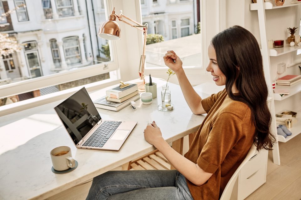 Woman sitting at a table, looking at a Surface Laptop