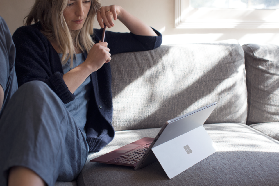 Woman sitting at home on sofa using Surface Pro