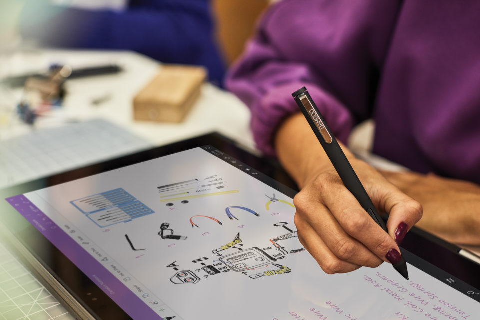 woman using stylus on Microsoft laptop, with OneNote program open