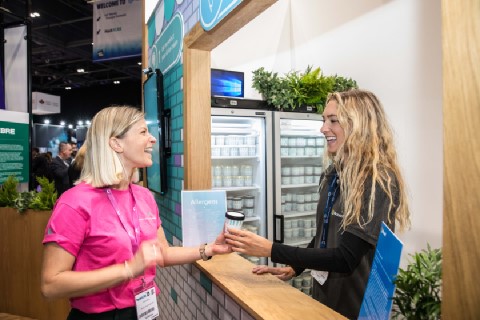 A woman receives an ice cream at Microsoft's AI stand at the ExCeL