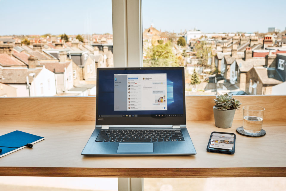 Microsoft device on a table by a window with houses in background