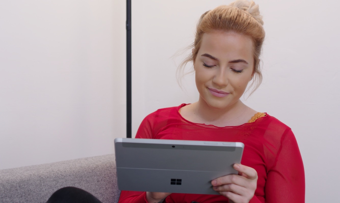 A girl sits at home looking at a Microsoft Surface tablet