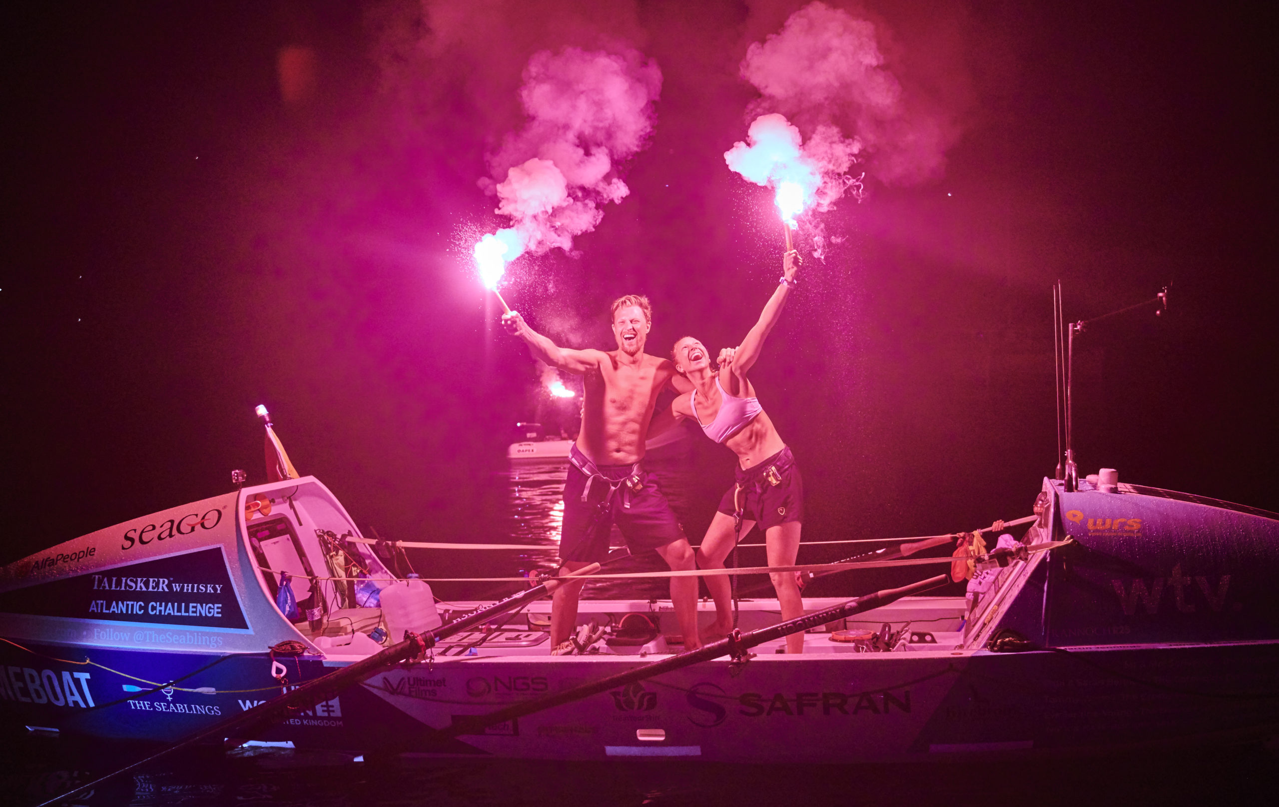 Anna and Cam McLean celebrate finishing their row across the Atlantic by lighting flares