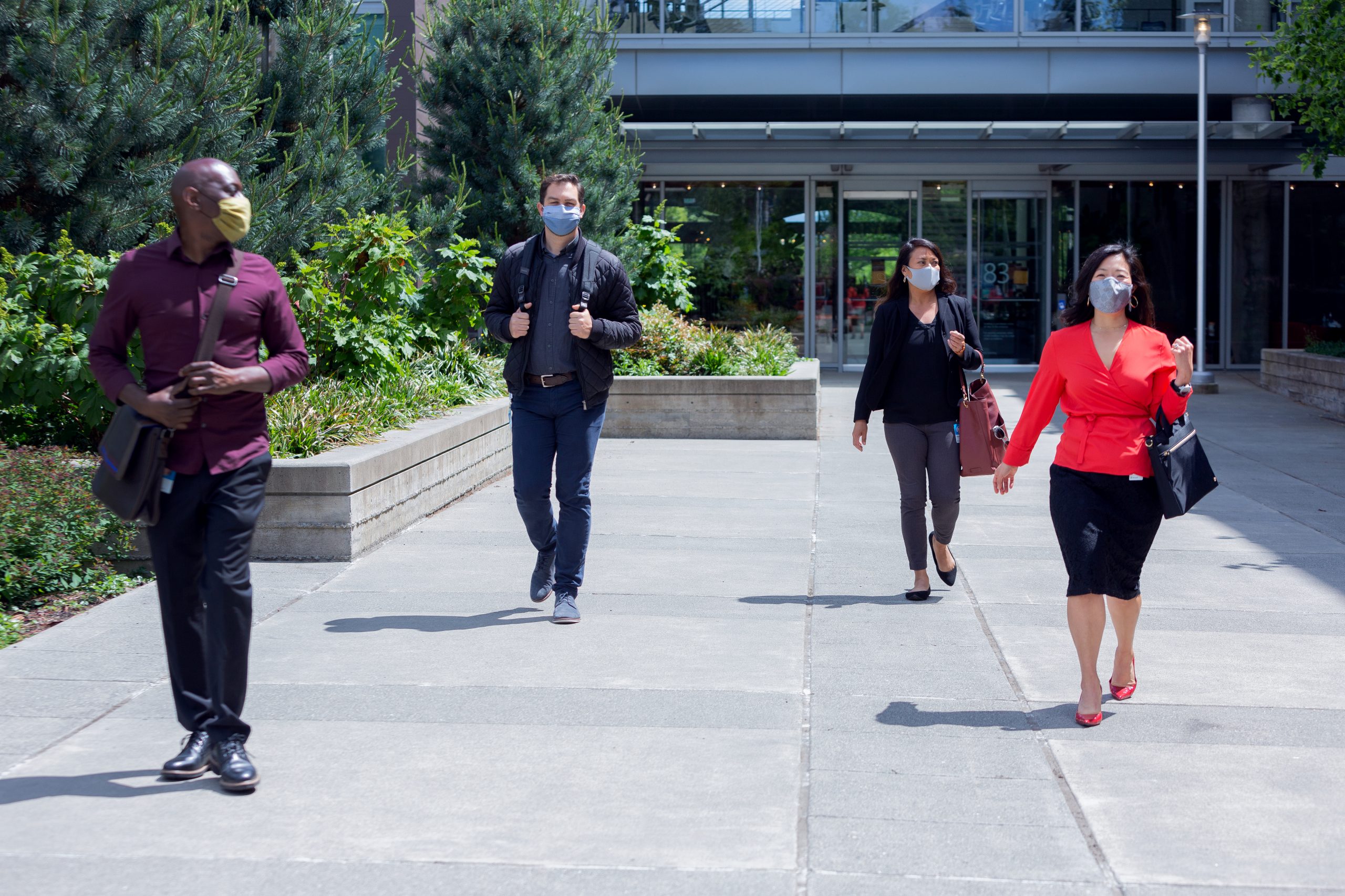 people wearing face masks walk out of an office building