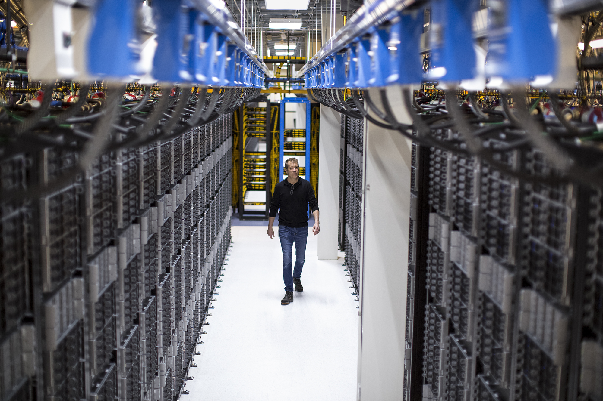 Man walking between racks of servers in data centre