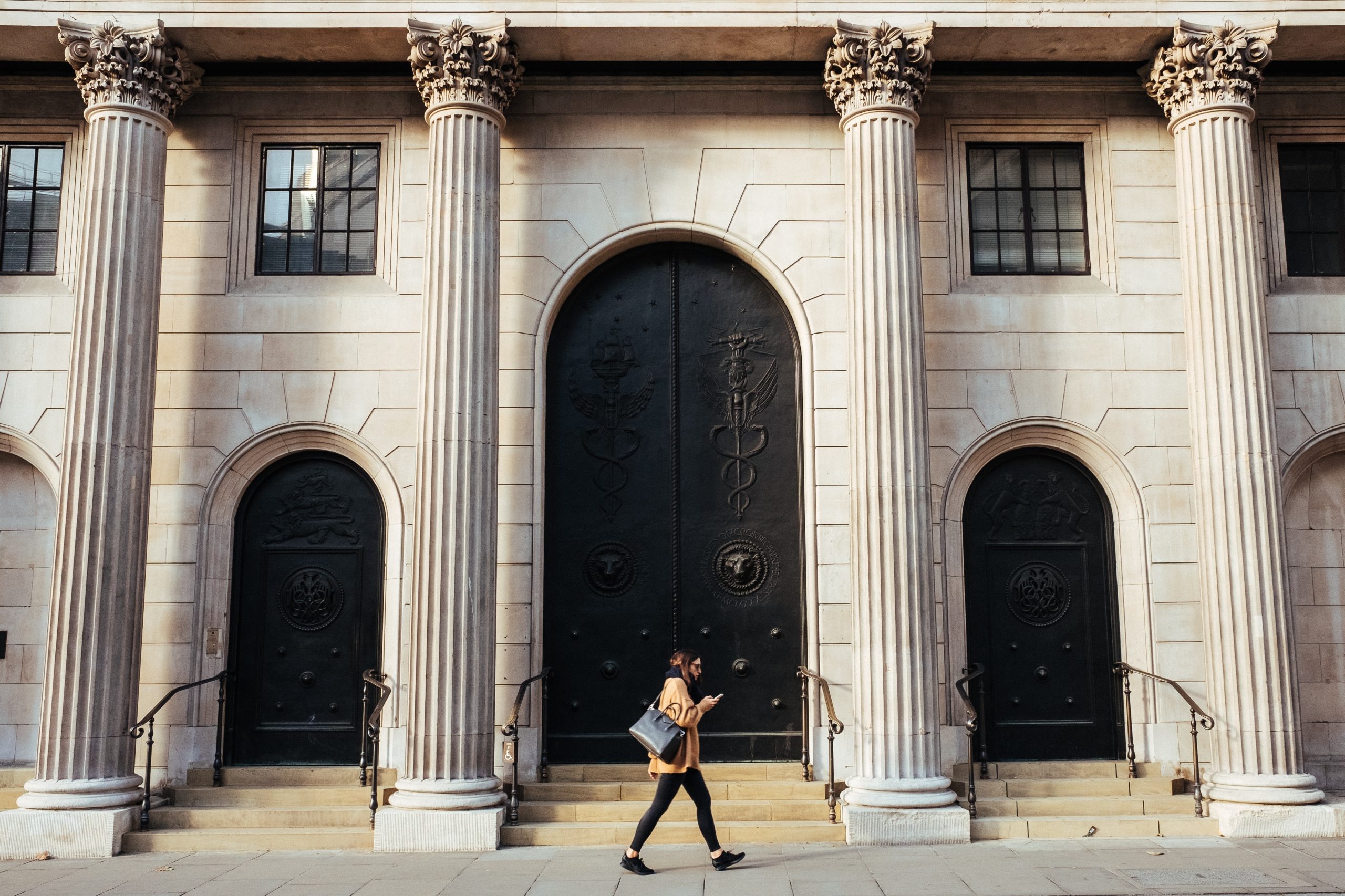 A woman walks past the doors to the Bank of England