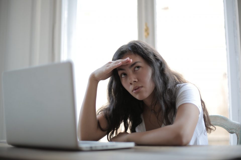 Woman working from home, sitting in front of a laptop, looking stressed