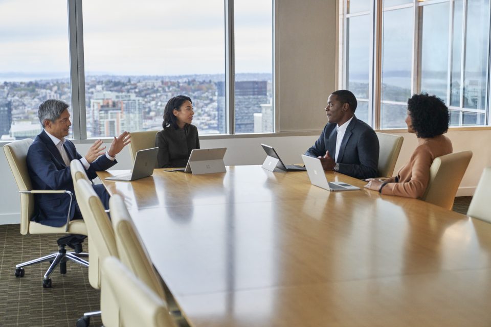 Four professionals sit around a table in a boardroom