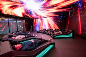 The immersive Xbox Power Your Dreams experience in London shows people lying on individual bed pods as they are surrounded by HD images of gaming scenescapes on the ceiling and walls.