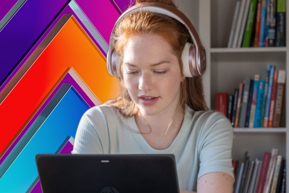 A woman wearing headphones looks at her laptop