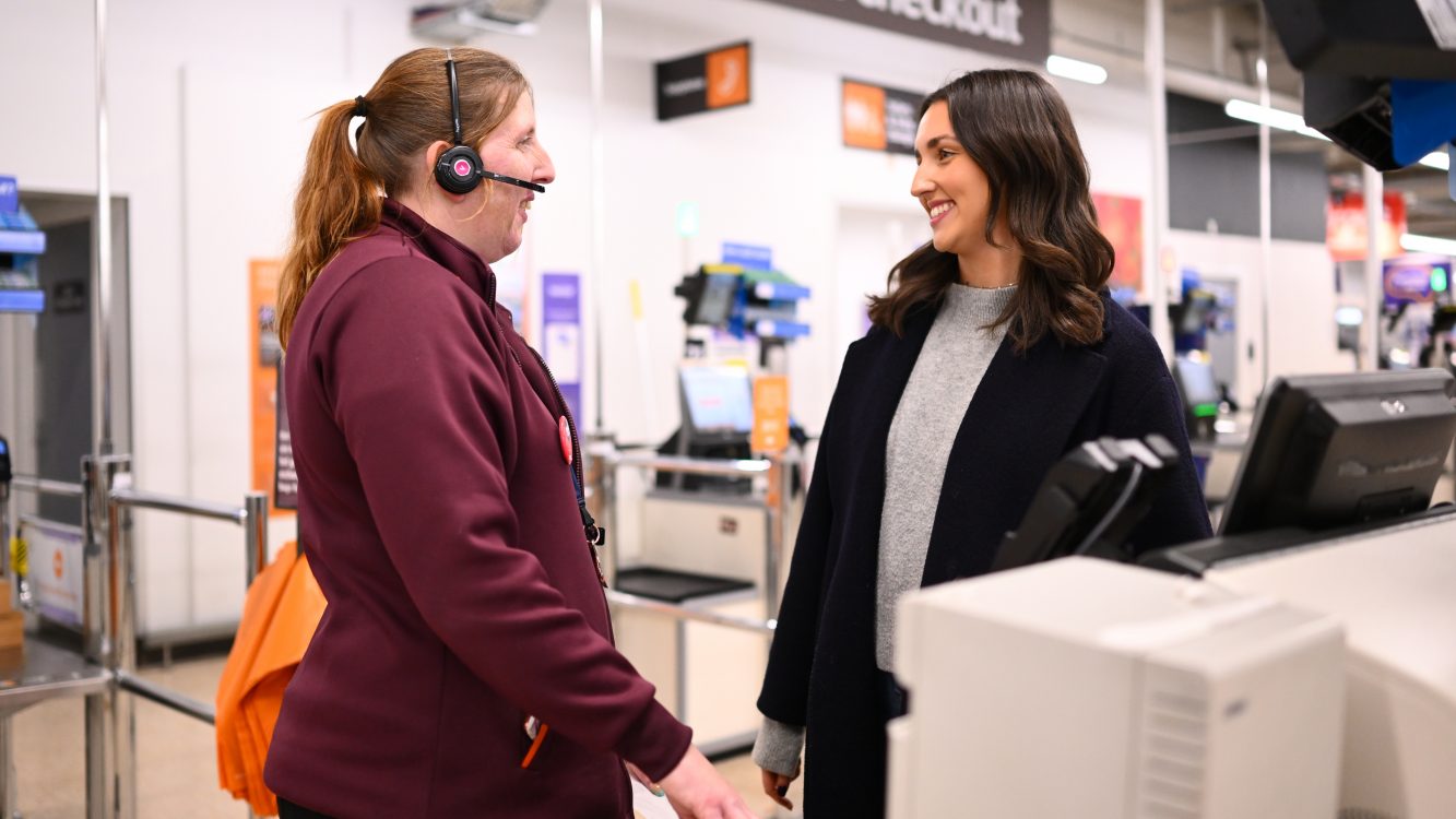 Young woman talking to Sainsbury's employee at the self checkout