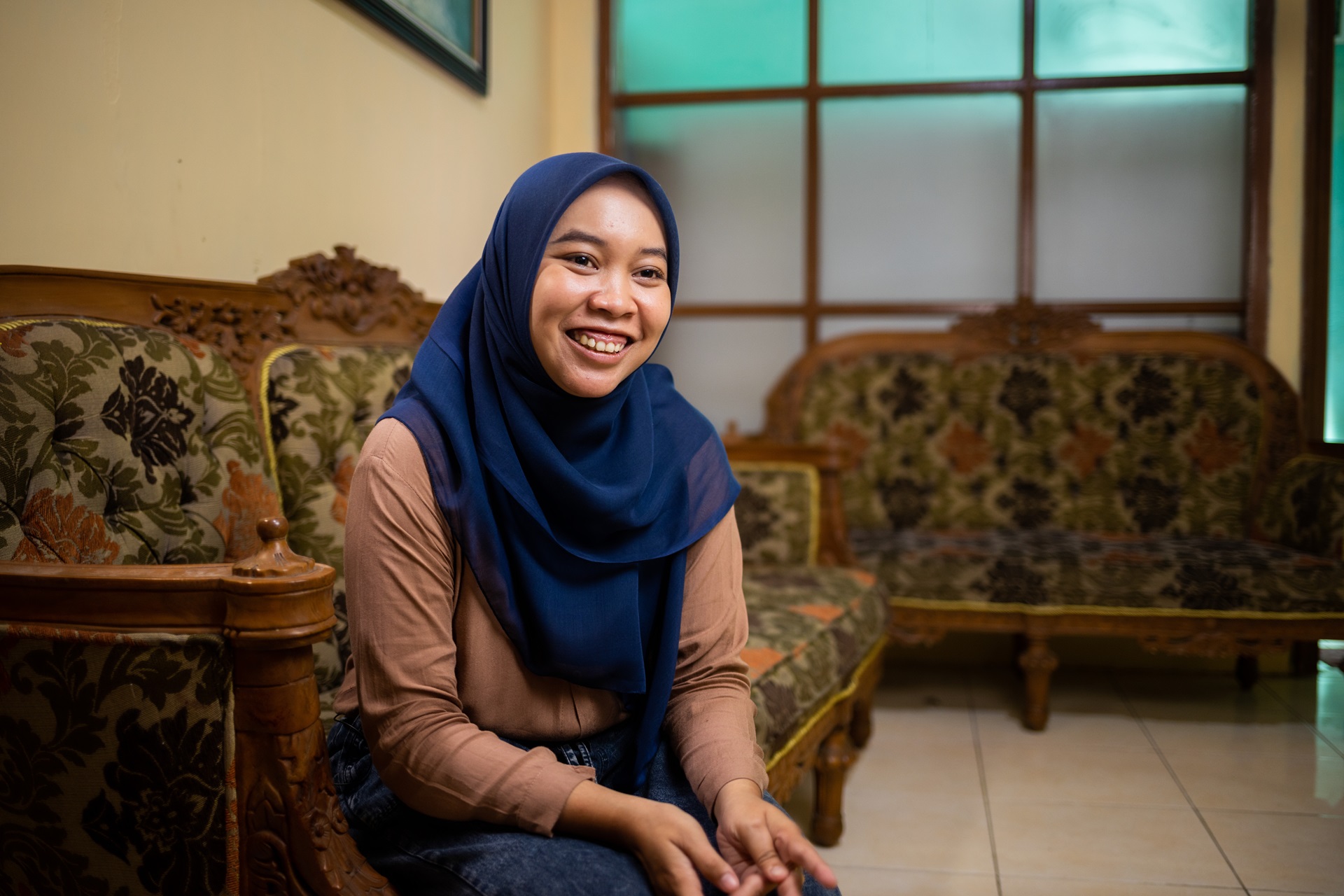 Woman in a headscarf sitting on a couch, smiling