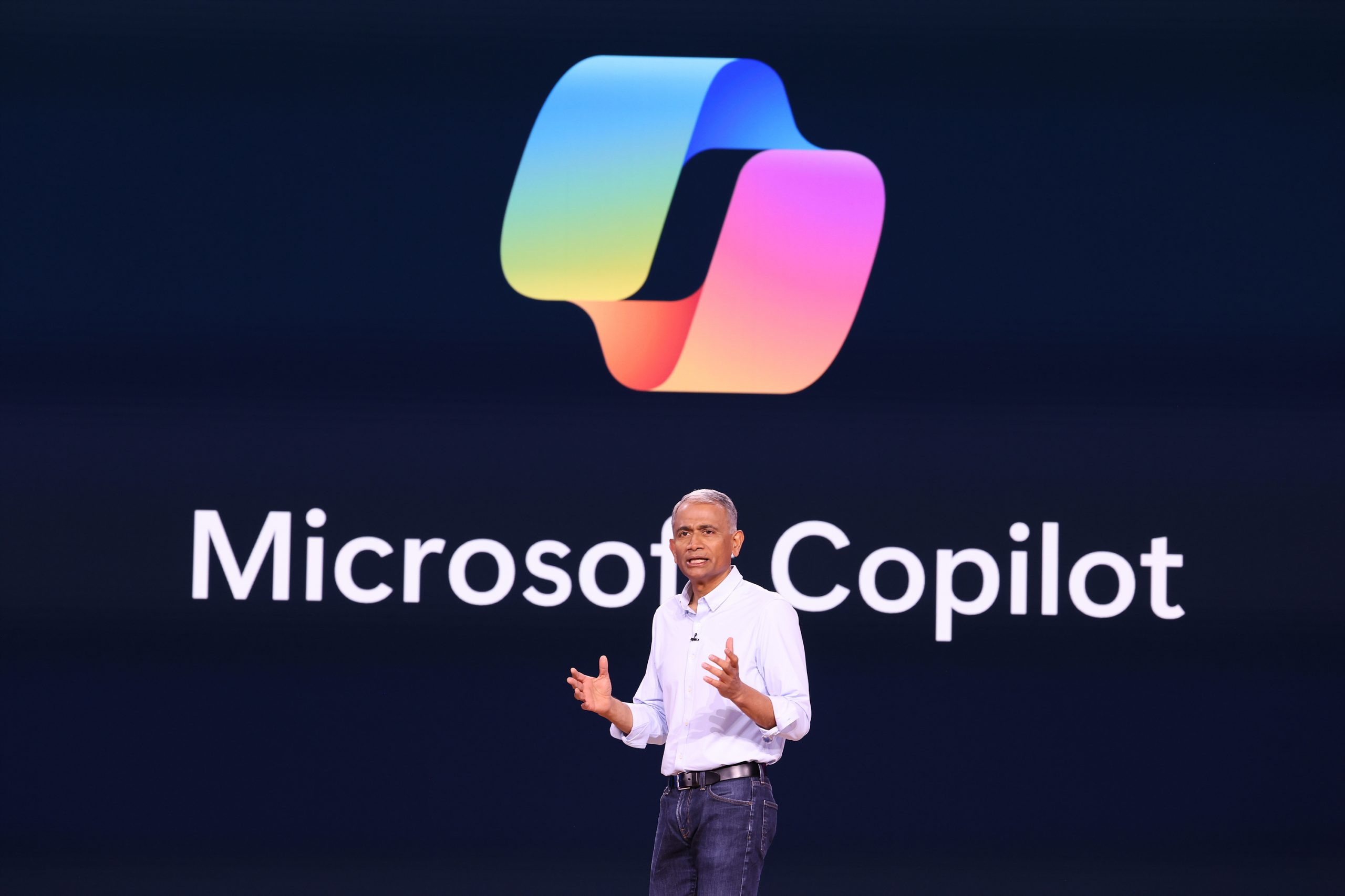 A man standing on stage with the Microsoft Copilot logo on a screen behind him