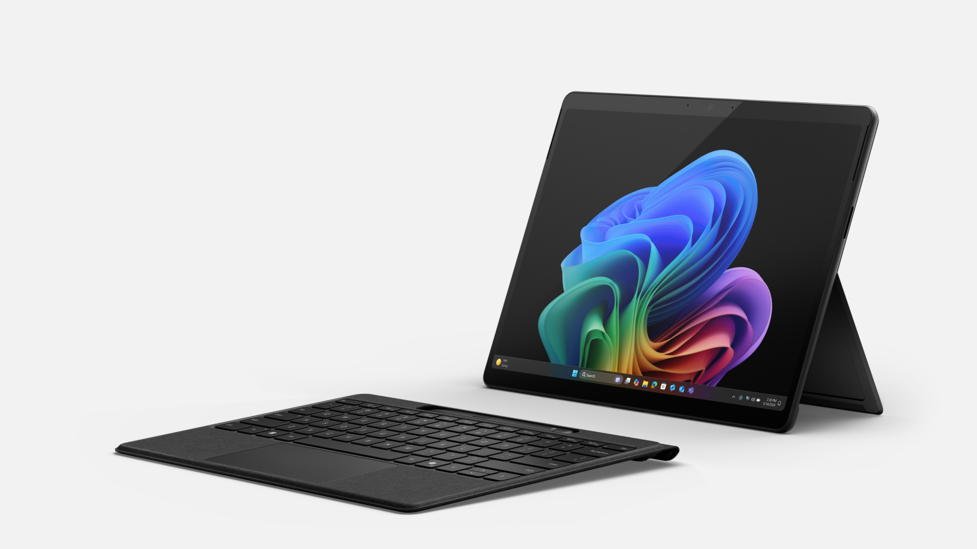 Angled front view of a black Surface Pro for Enterprise with the Windows rainbow bloom image on the home page in dark mode including a detached black Surface Pro Keyboard.