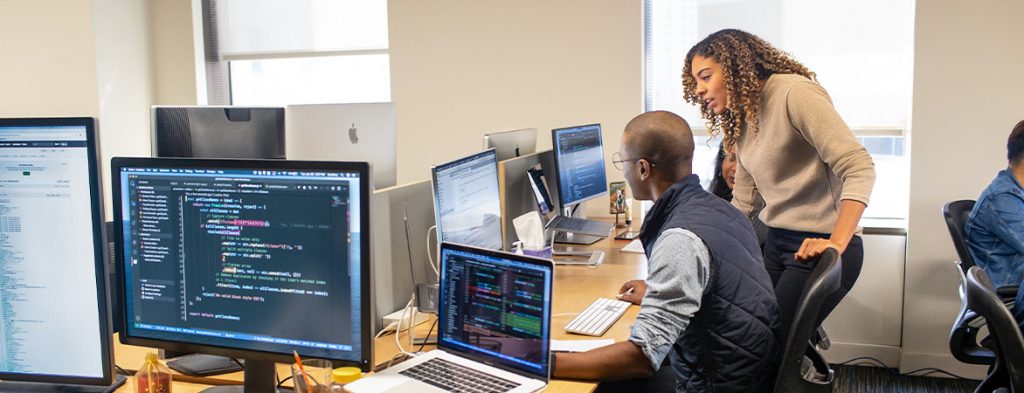 A group of people work together over a computer in an office