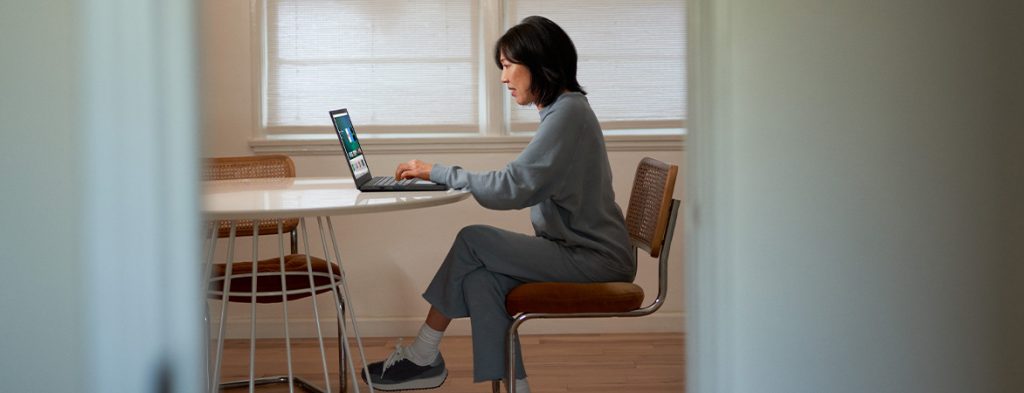 A woman sits at a table working on a laptop