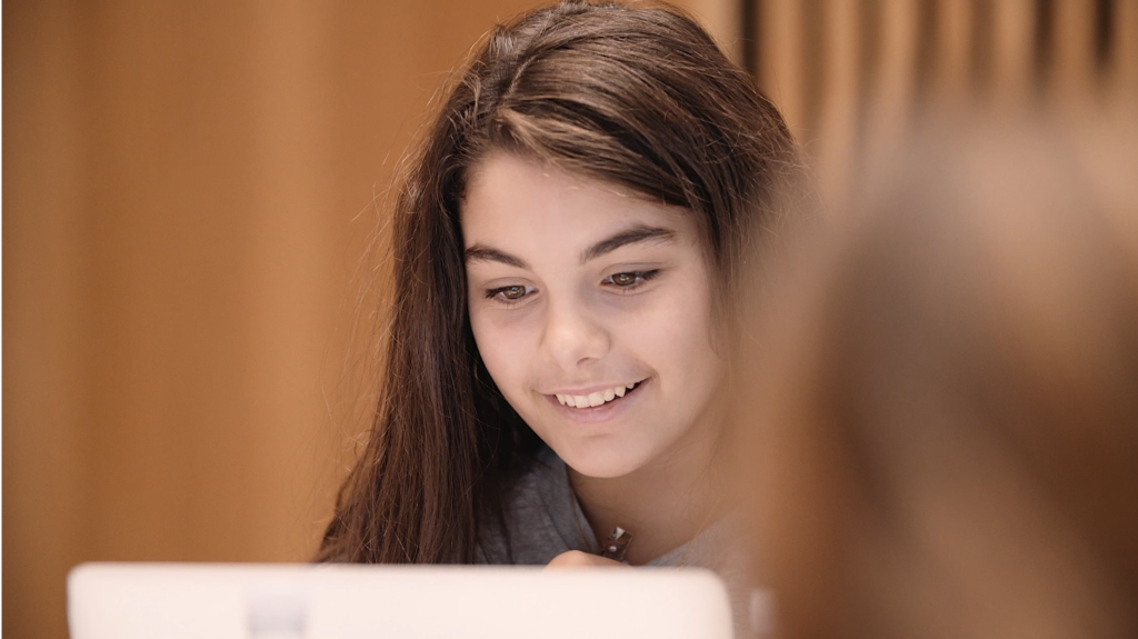 Girl smiling at laptop screen