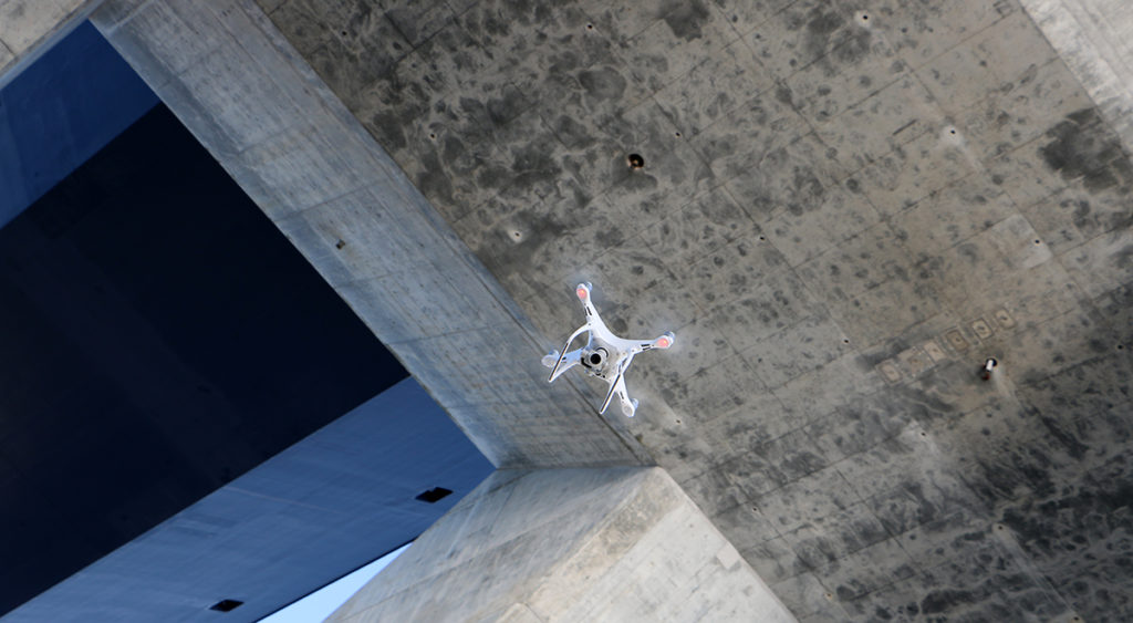 Drone flying beneath a concrete bridge
