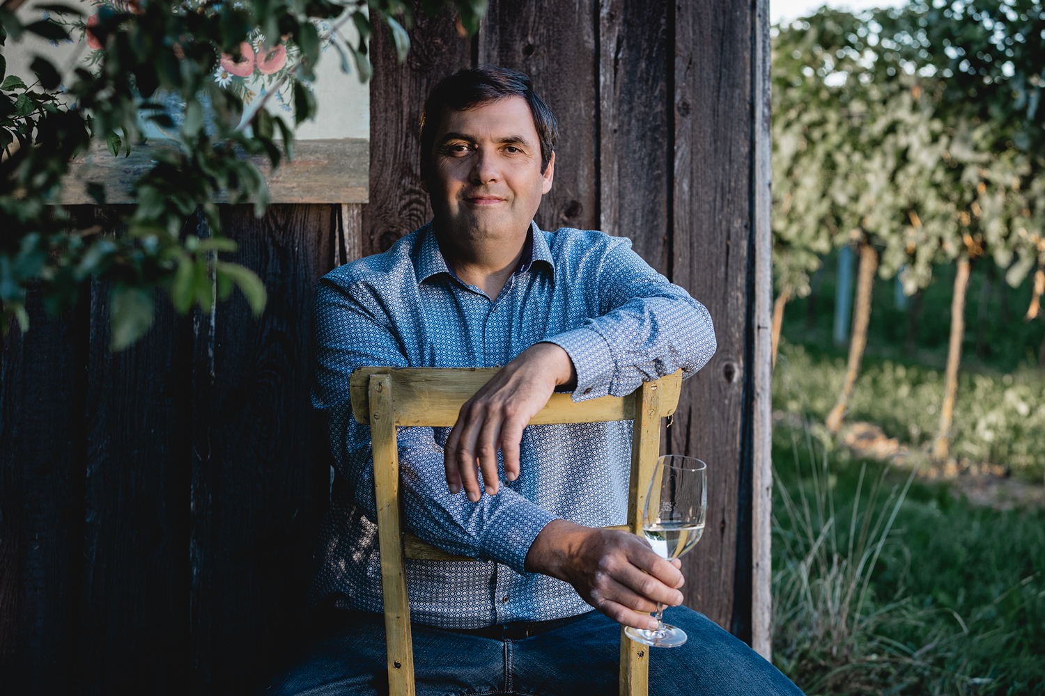 A man sits on a chair holding a wine glass