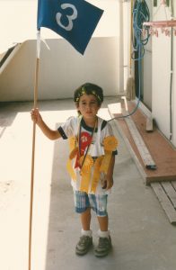photo of five-year-old Andy Bryant holding a flag and draped with colorful ribbons and medals